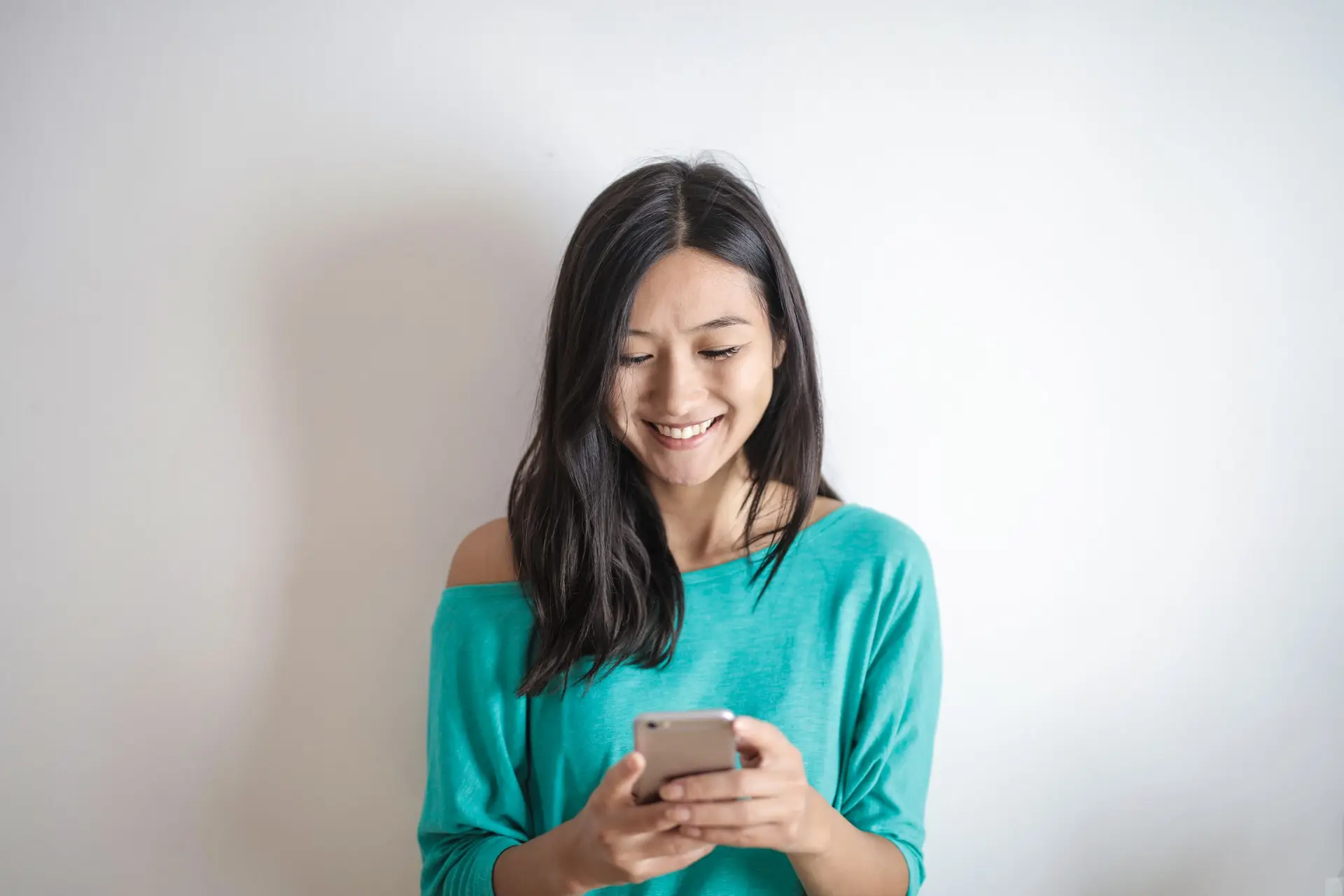 Eine lächelnde Frau schaut auf ihr Smartphone und plant einen Termin